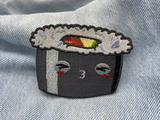 Schwarzer Kawaii Sushi Roll Patch auf blauer Jeans