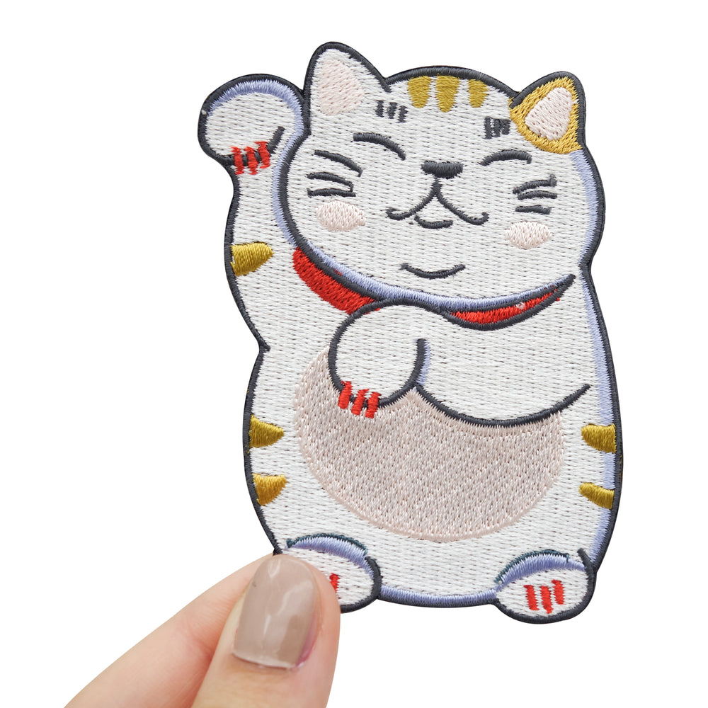Hand hält Glückskatzen Patch