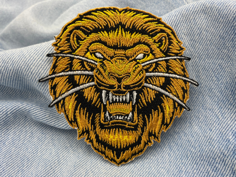 Gelber Löwenkopf Patch auf blauer Jeans