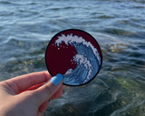 Wellen Patch gehalten von einer Frauenhand mit dem Meer im Hintergrund