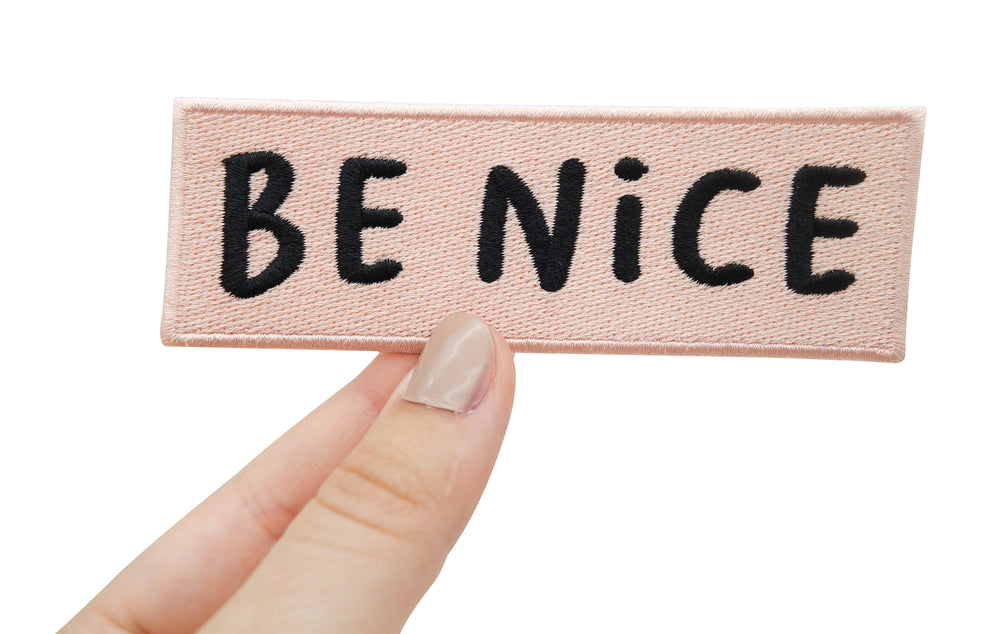 Frauenhand hält rosa Be Nice Patch