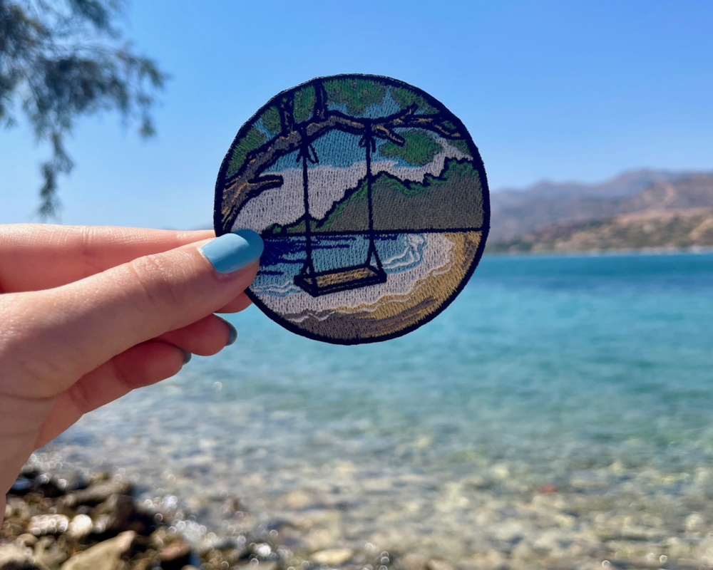 Strand Schaukel Patch mit Meer im Hintergund gehalten von einer Frauenhand