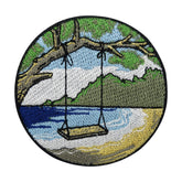Schaukel am Strand mit Meer und Bergen im Hintergund Patch