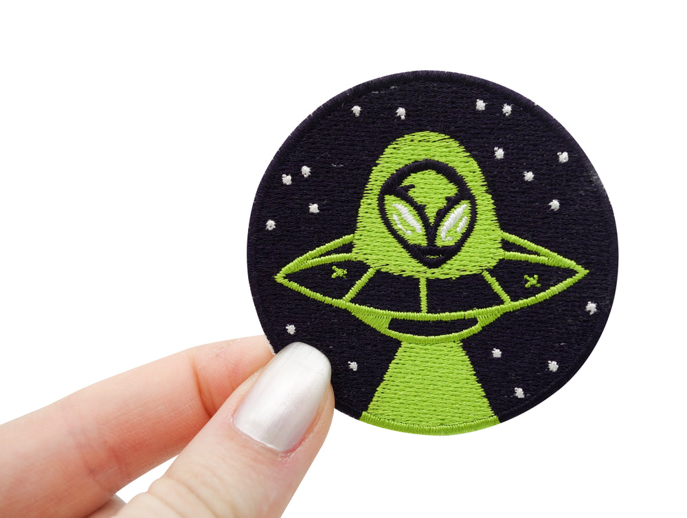 Frauenhand hält den Alien im Ufo Patch