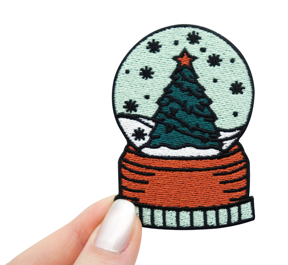 Frauenhand hält den Schneekugel Patch