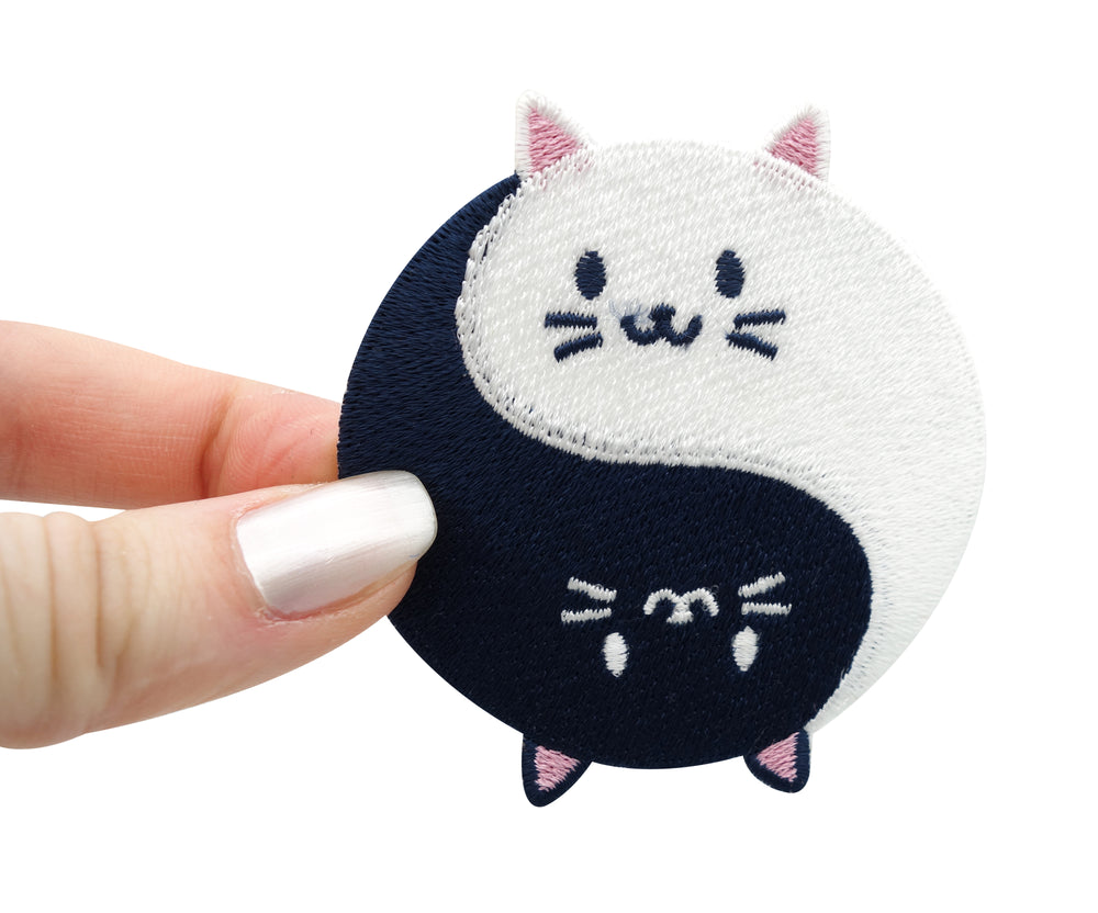 Yin & Yang Katzen Patch gehalten von einer Frauenhand