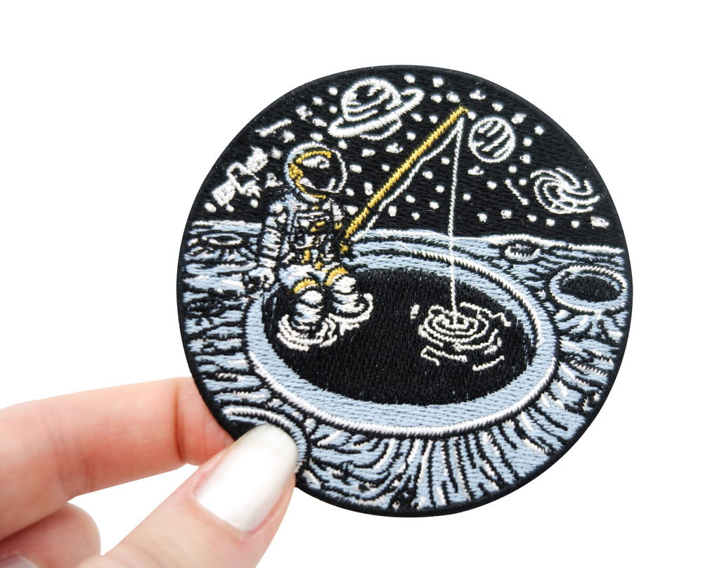 Frauenhand hält den angelnden Astronauten Patch