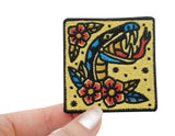 Schlange mit Blumen Patch gehalten von einer Frauenhand