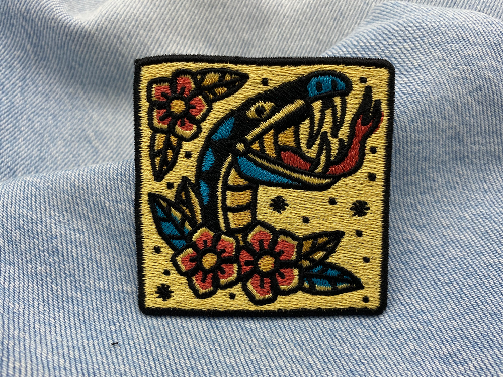 Schlange mit Blumen Patch auf blauer Jeans