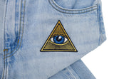 Illuminati Patch auf heller blauer Jeans aufgebügelt
