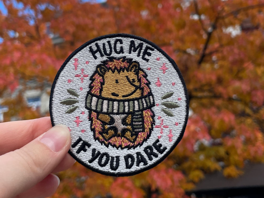 Igel Patch gehalten von einer Frauenhand vor herbstlichem Hintergrund