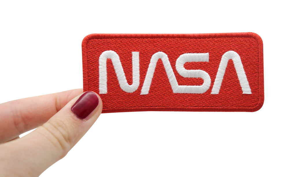 Frauenhand hält den NASA Patch