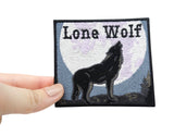 Frauenhand hält den Lone Wolf Patch