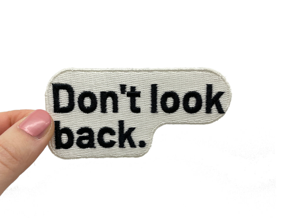 Frauenhand hält den Don´t look Back Patch