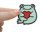 Frosch mit Herz Patch gehalten von einer Frauenhand