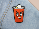 Bier Pong Becher Patch auf hellblauer Jeans aufgebügelt