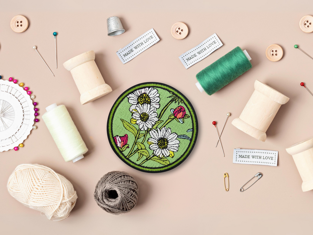 Grüner Blumen Patch mit Nähzeug im Hintergrund