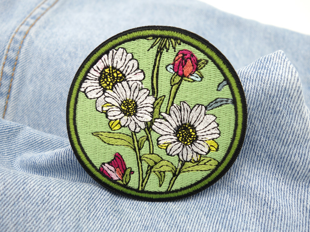 Grüner Blumen Patch auf hellblauer Jeans