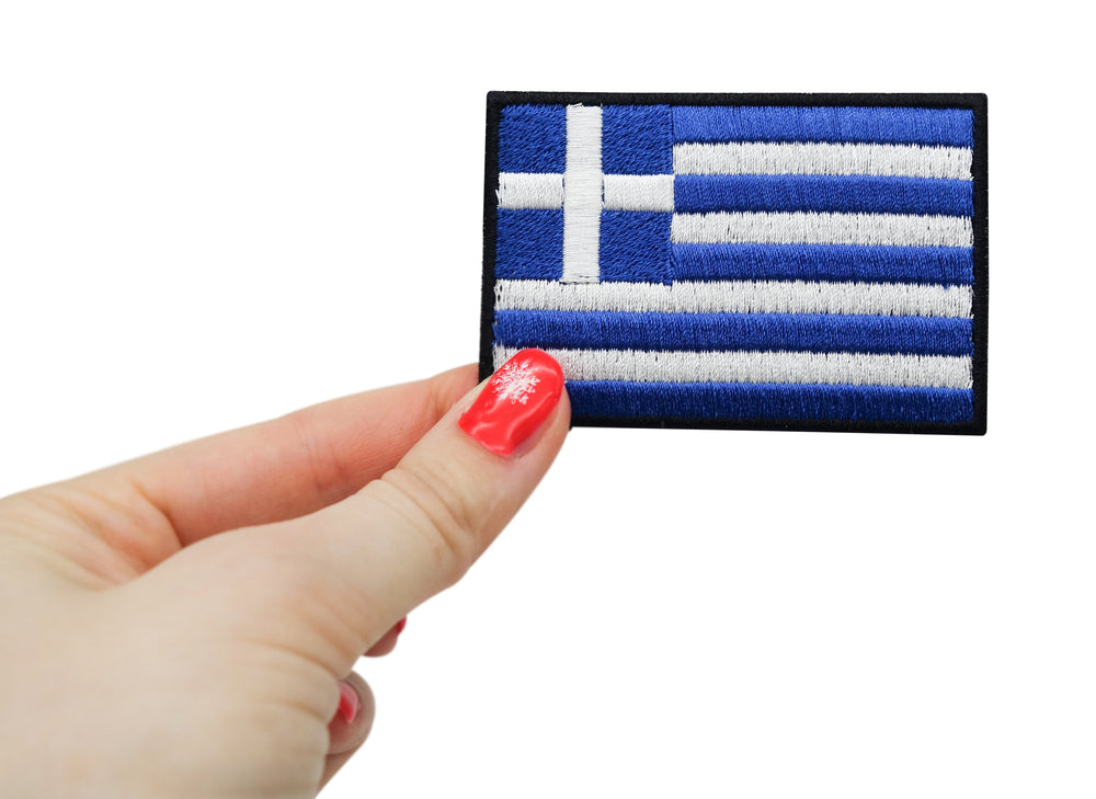 Frauenhand hält den Griechenland Flagge Klettpatch
