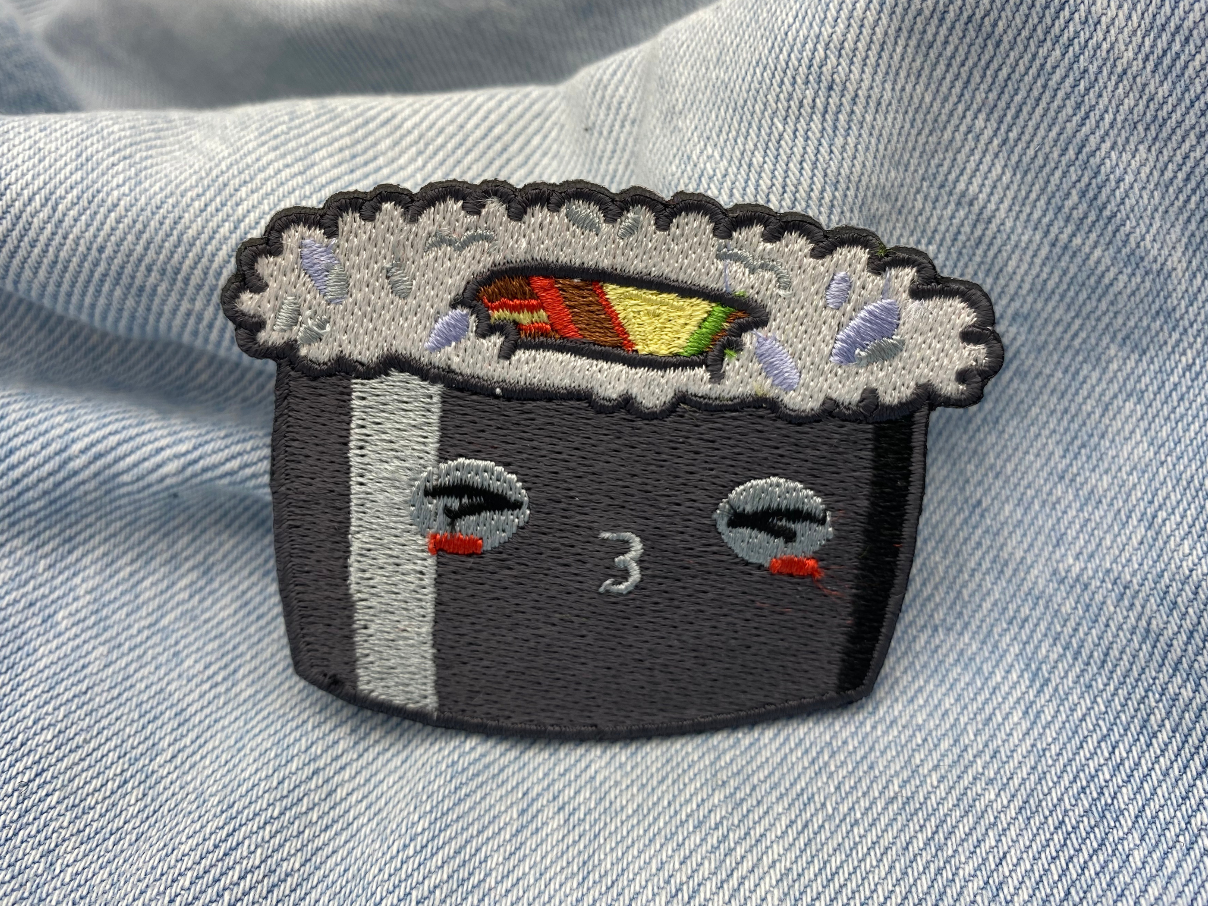 Schwarzer Kawaii Sushi Roll Patch auf blauer Jeans