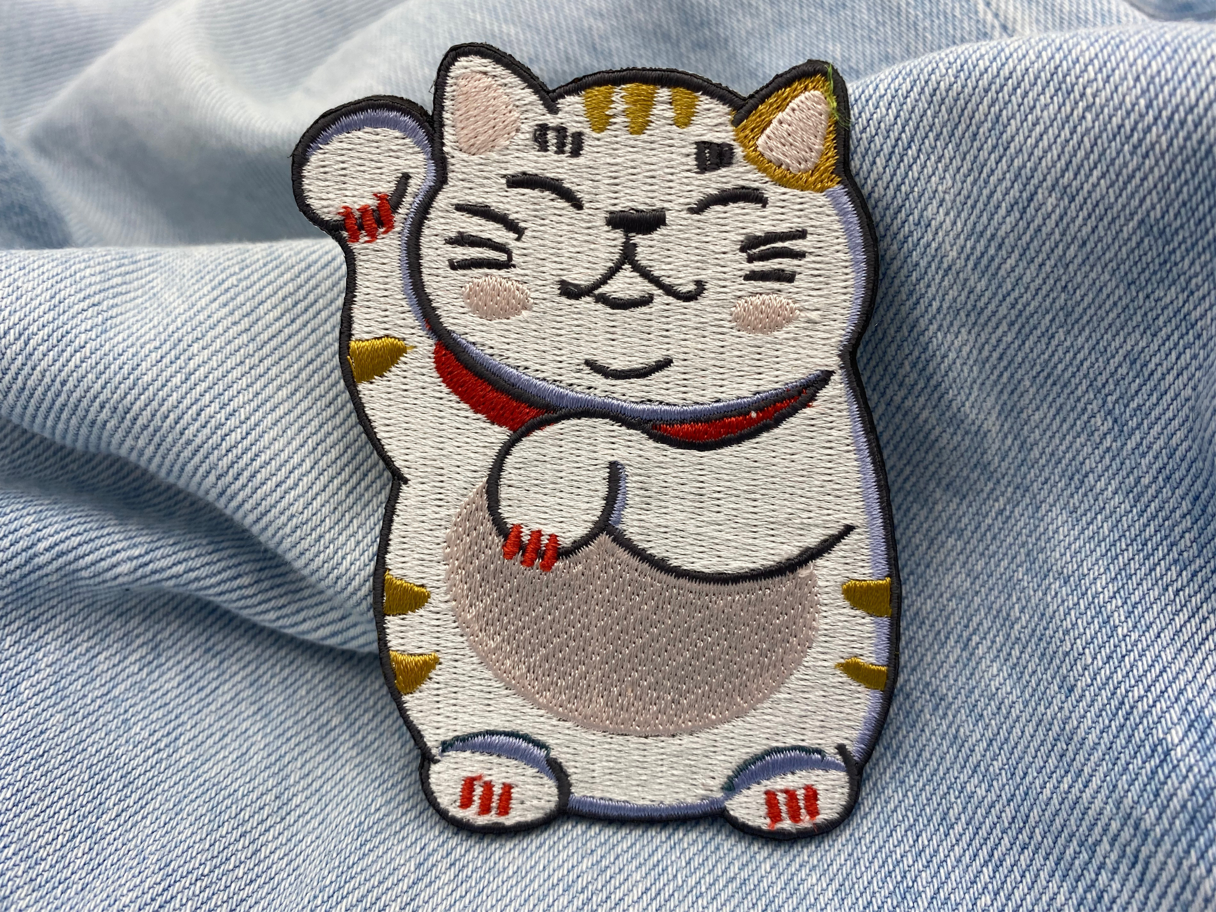 Glückskatzen Patch auf blauer Jeans