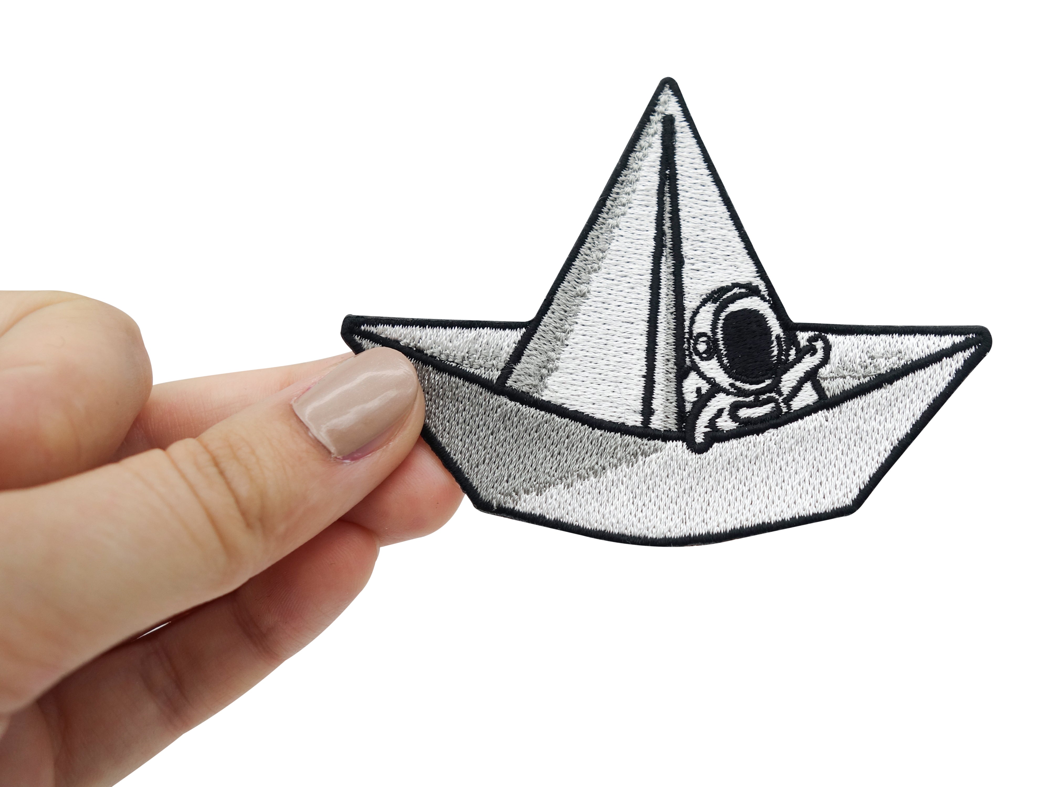 Weibliche Hand hält den Astronauten-Patch in Weiß.