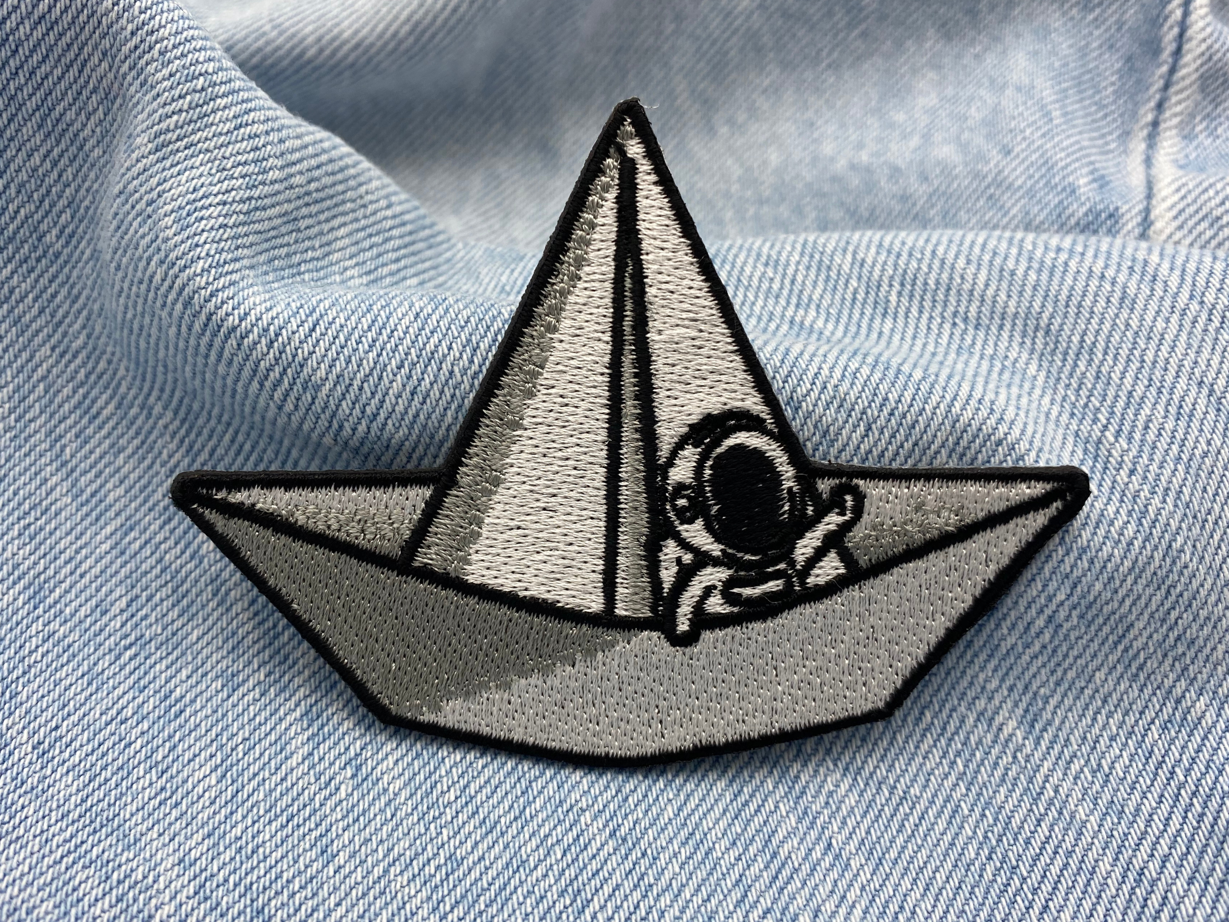 Astronauten-Patch auf blauer Jeans für stylischen Weltraum-Look.