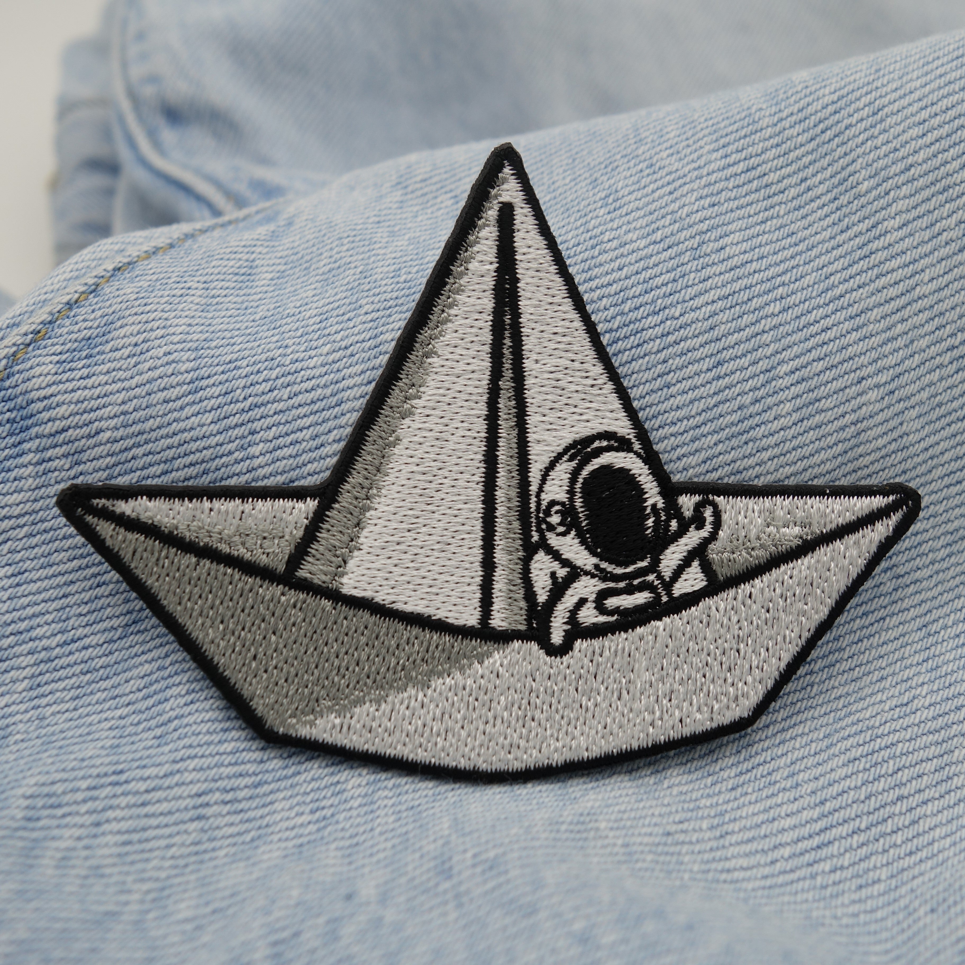 Astronauten-Patch auf blauer Jeans für stylischen Weltraum-Look.