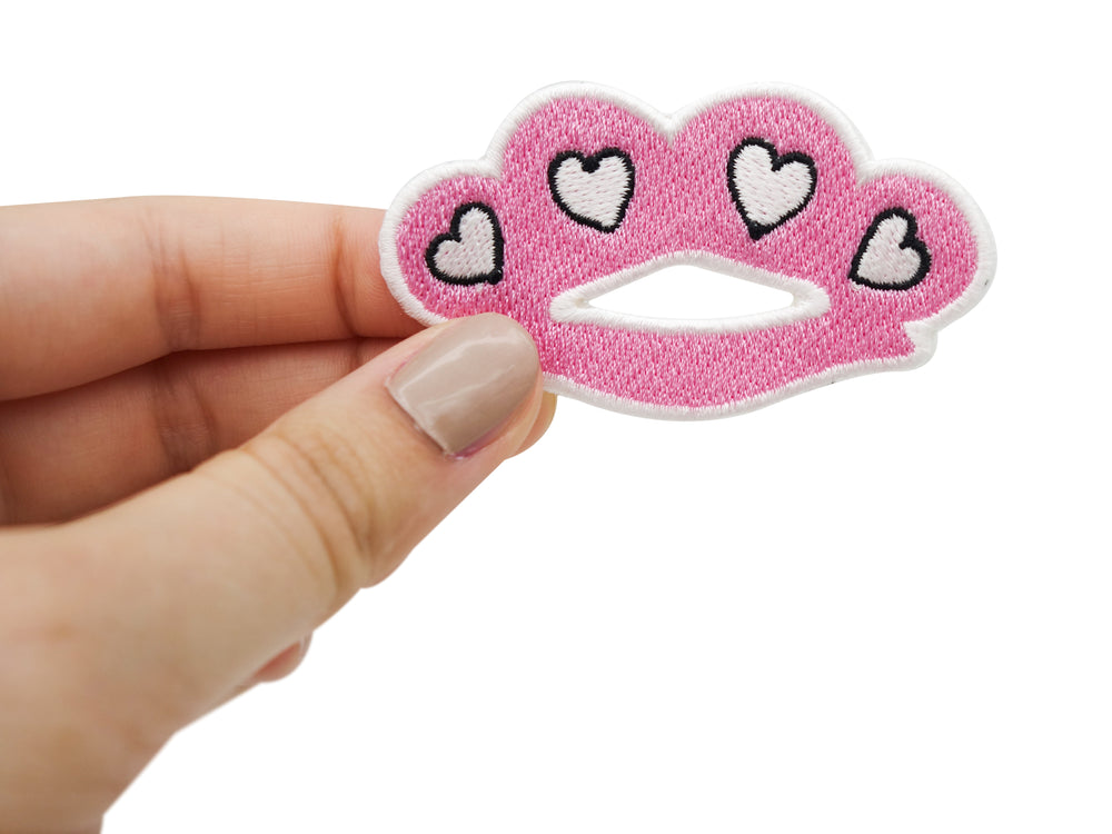 Frauenhand hält den rosa Schlagring-Patch