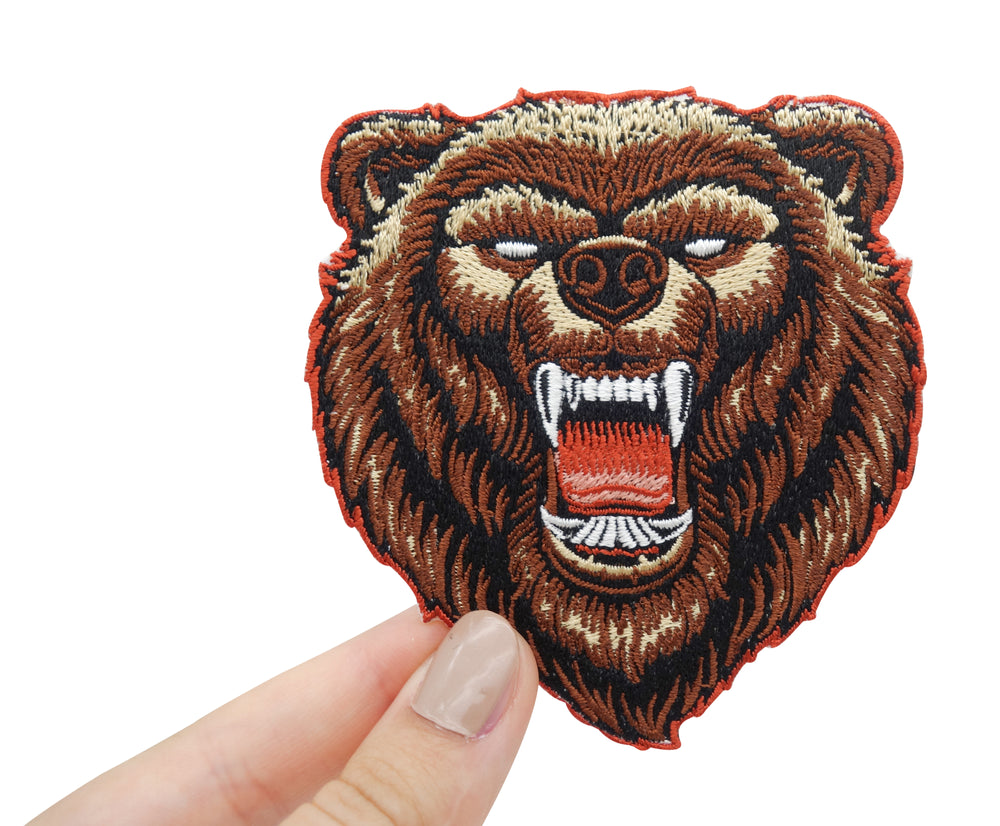 Frauenhand hält den Grizzly Bären Patch