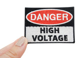 High Voltage Patch gehalten von einer Frauenhand 