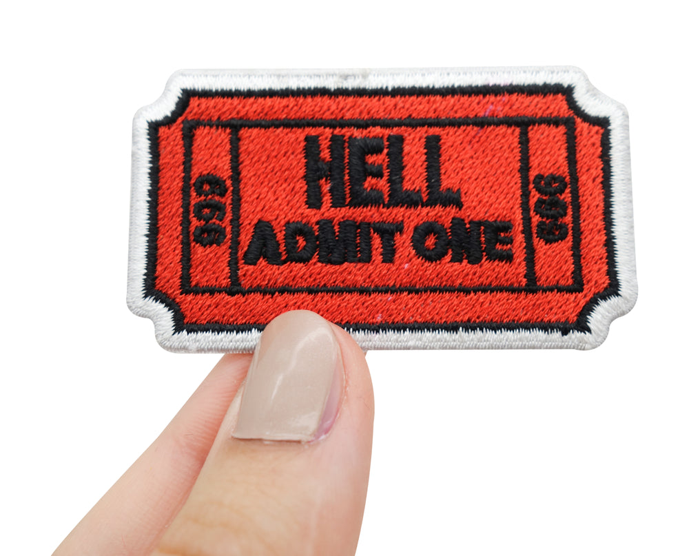 Höllen Ticket Patch gehalten von einer Frauenhand