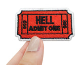 Höllen Ticket Patch gehalten von einer Frauenhand