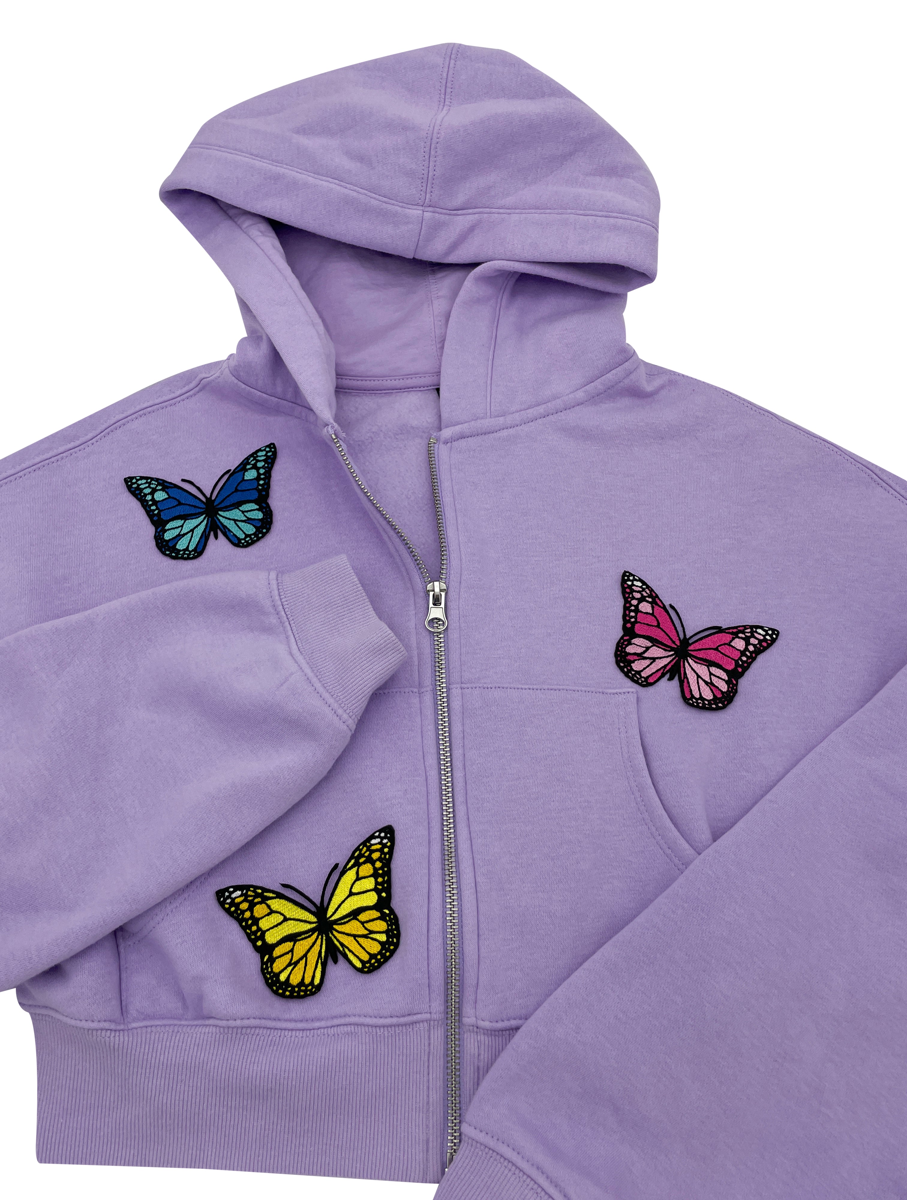 Drei Schmetterling Patches auf lila Pullover aufgebügelt