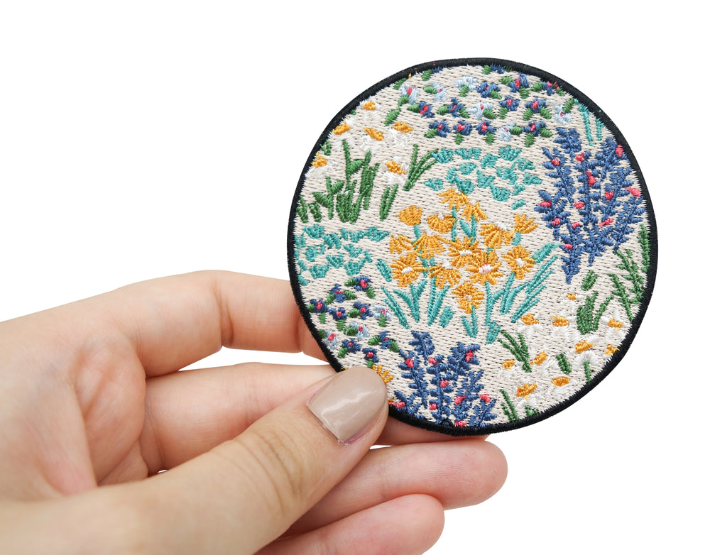 Frauenhand hält den Blumenwiesen Patch 