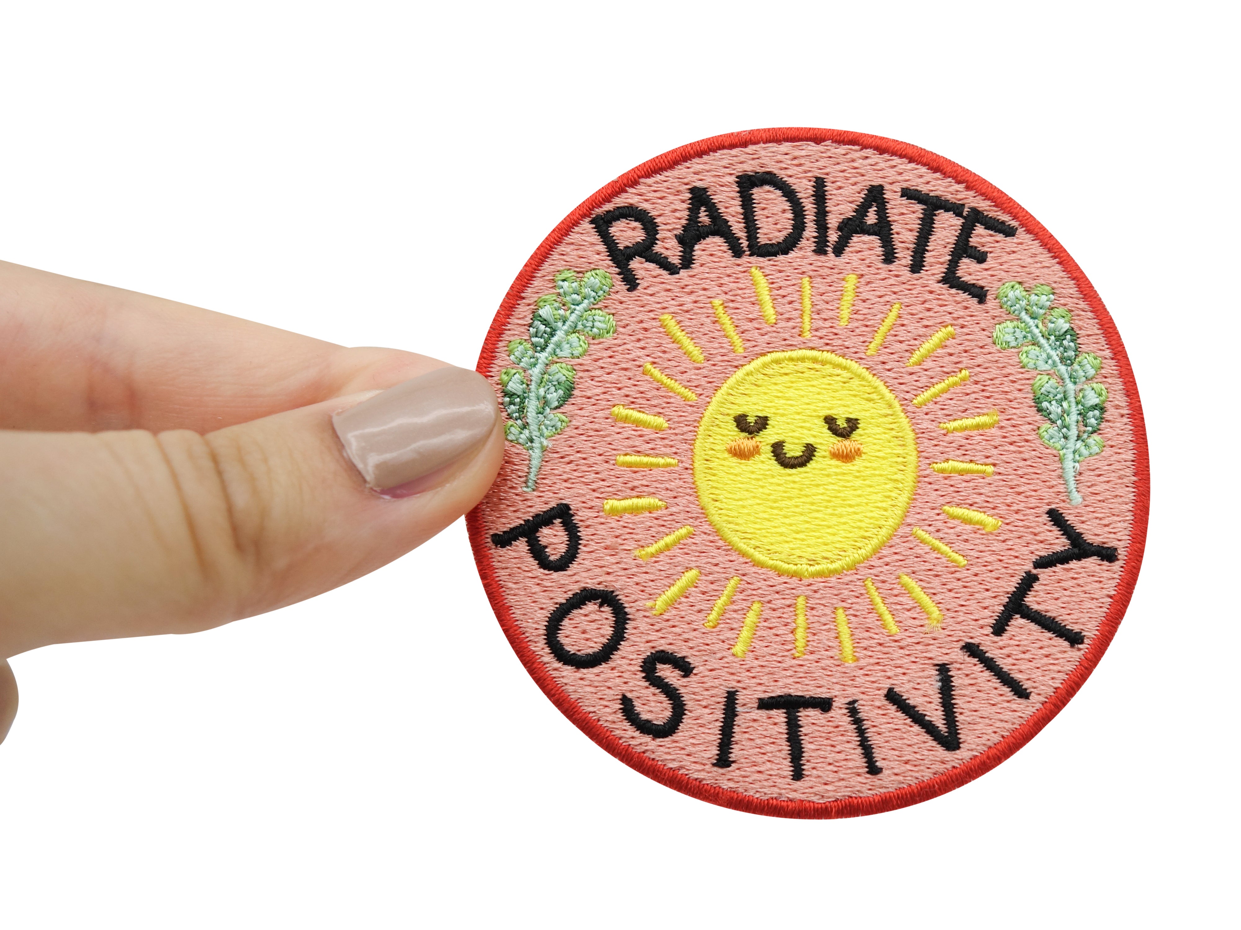 "Radiate Positivity" Patch gehalten von einer Frauenhand