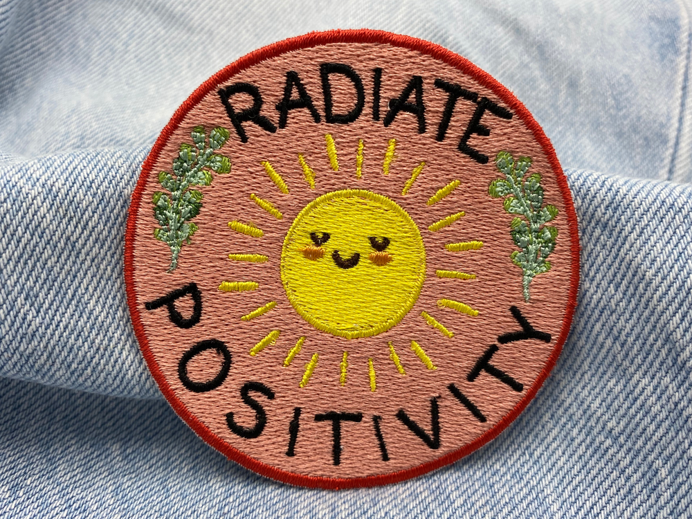 "Radiate Positivity" Patch auf blauer Jeans