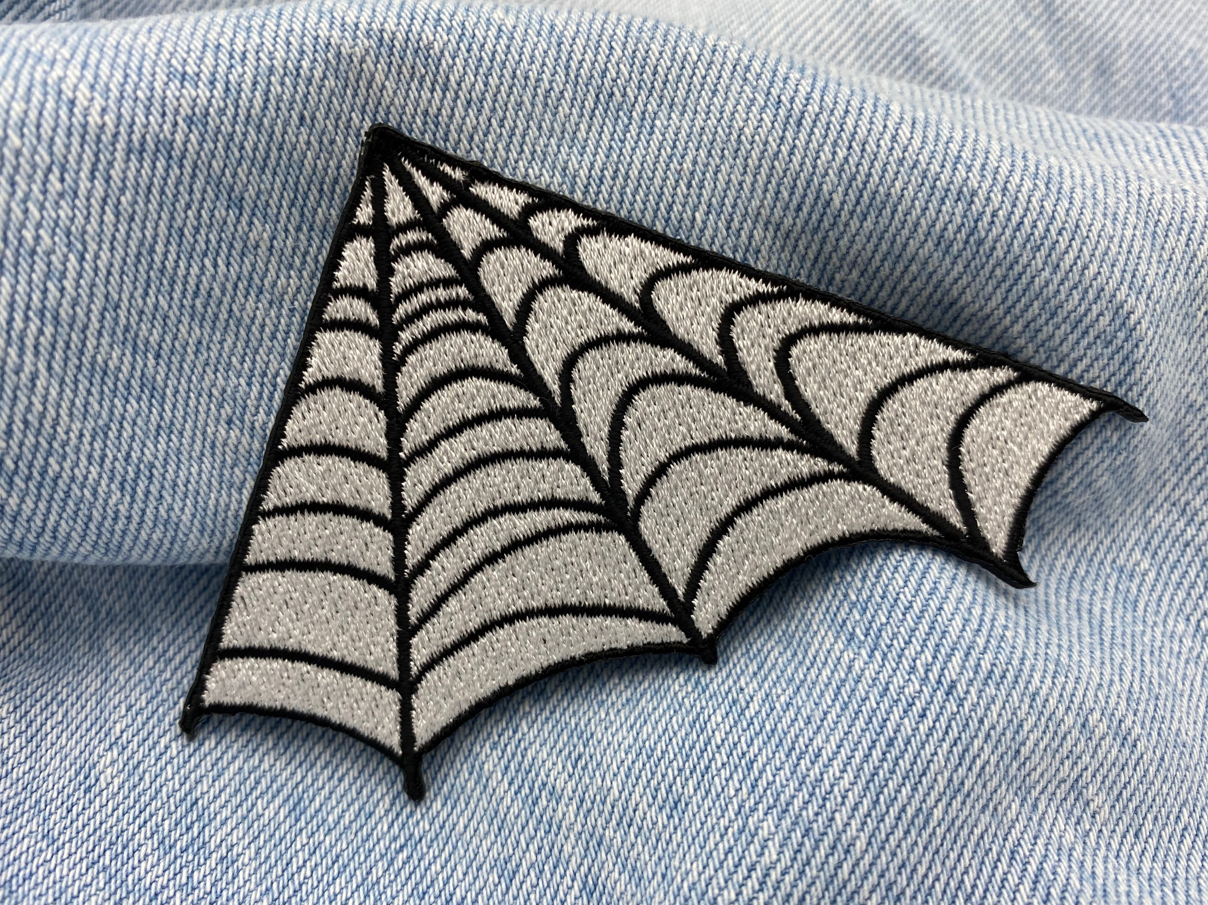 Spinnenweben Patch auf blauer Jeans