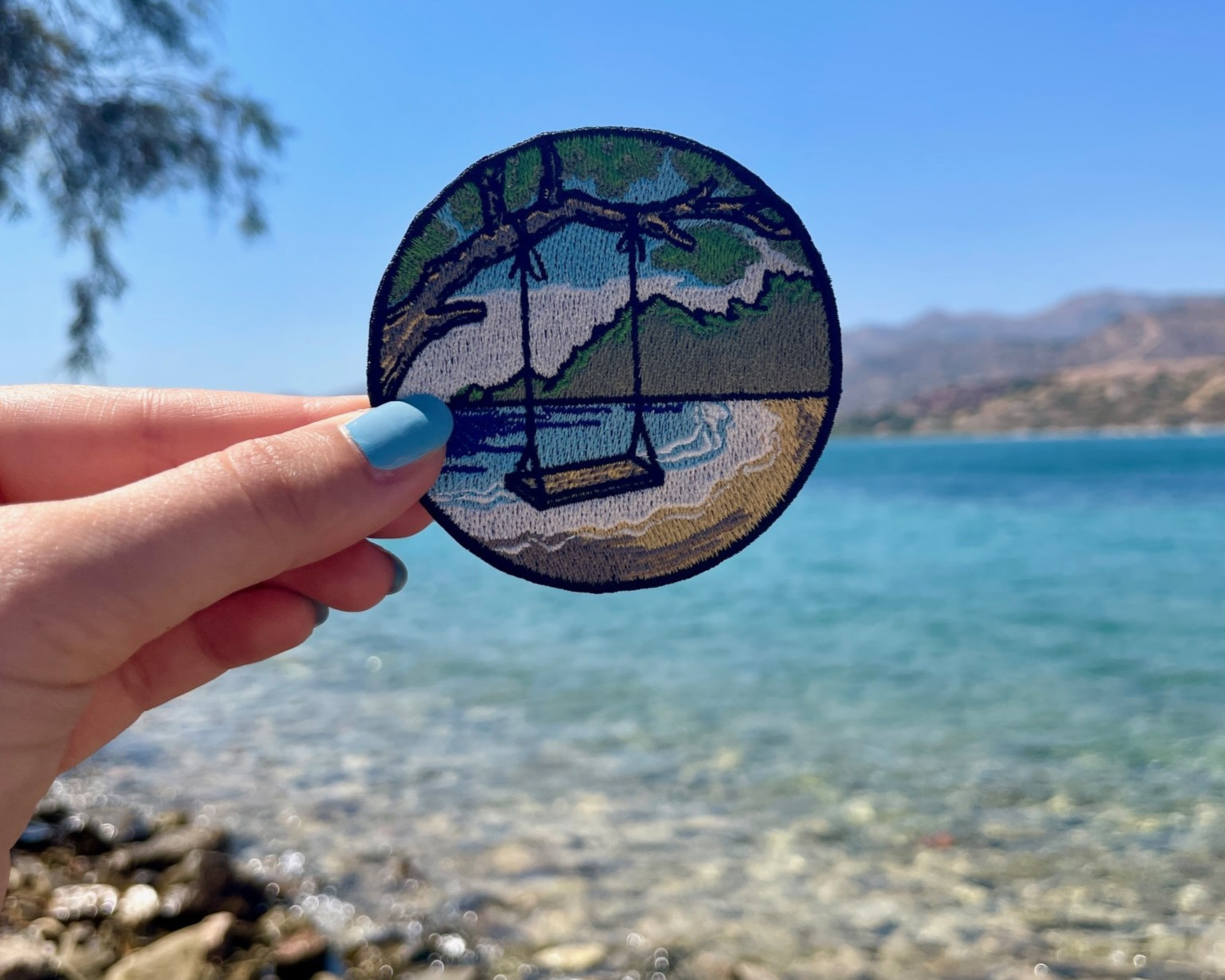 Strand Schaukel Patch mit Meer im Hintergund gehalten von einer Frauenhand