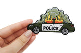 Frauenhand hält brennendes Polizeiauto Patch