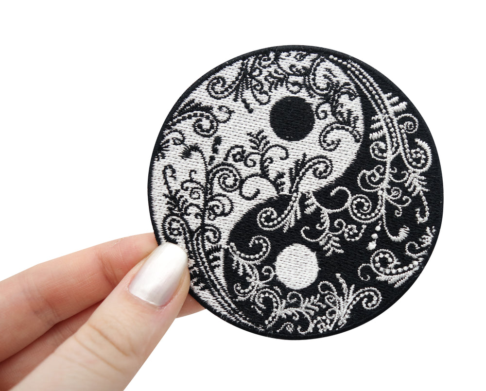 Frauenhand hält Yin Yang Blumen Patch.