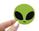 Alien Kopf Patch gehalten von einer Frauenhand