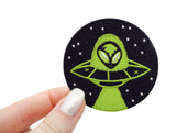 Frauenhand hält den Alien im Ufo Patch 