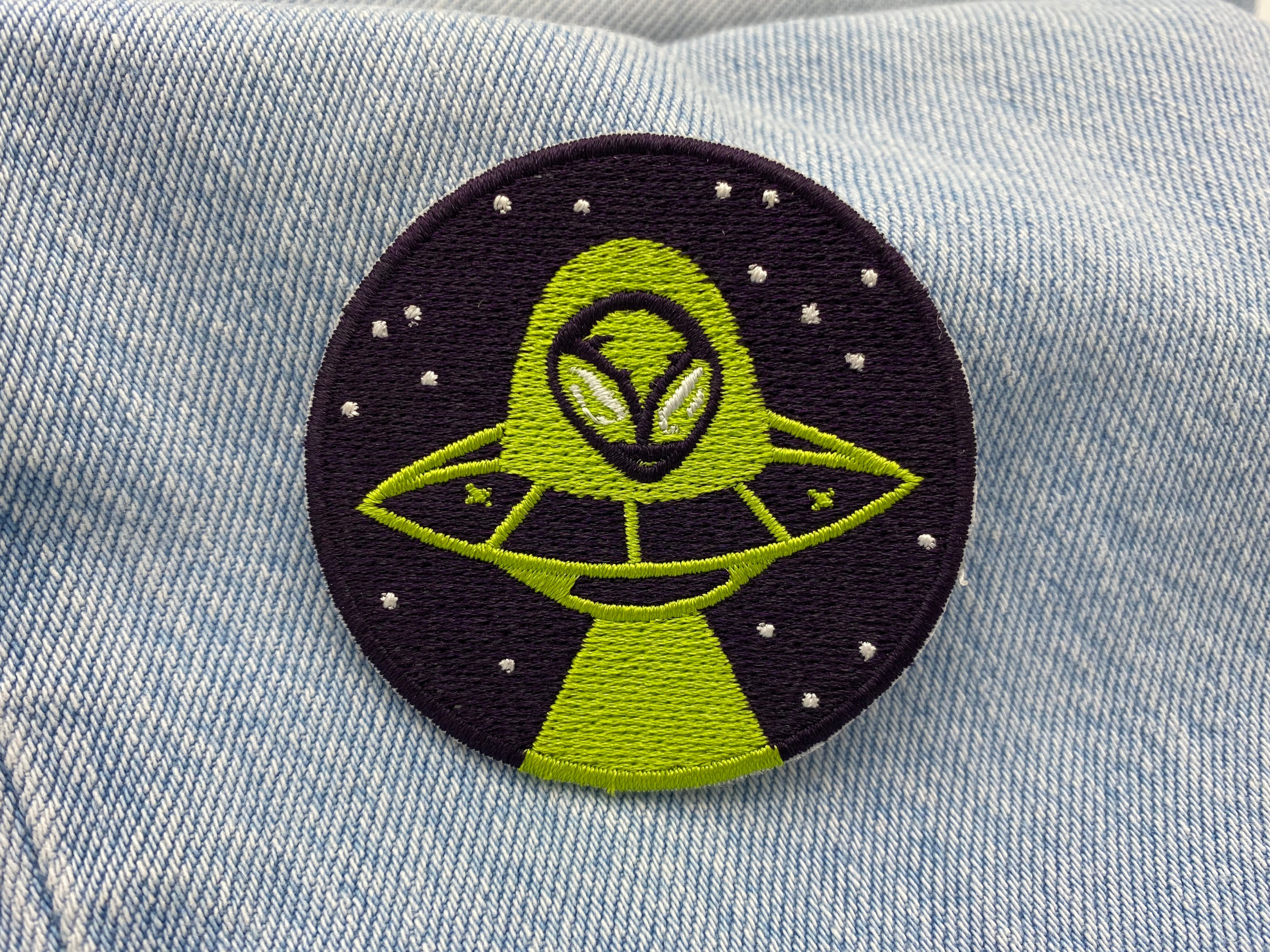 Alien im Ufo Patch auf blauer Jeans
