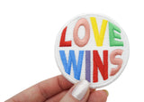 Frauenhand hält den Love Wins Patch