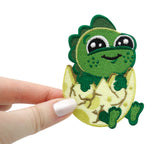 Frauenhand hält den Baby Dinosaurier Patch 