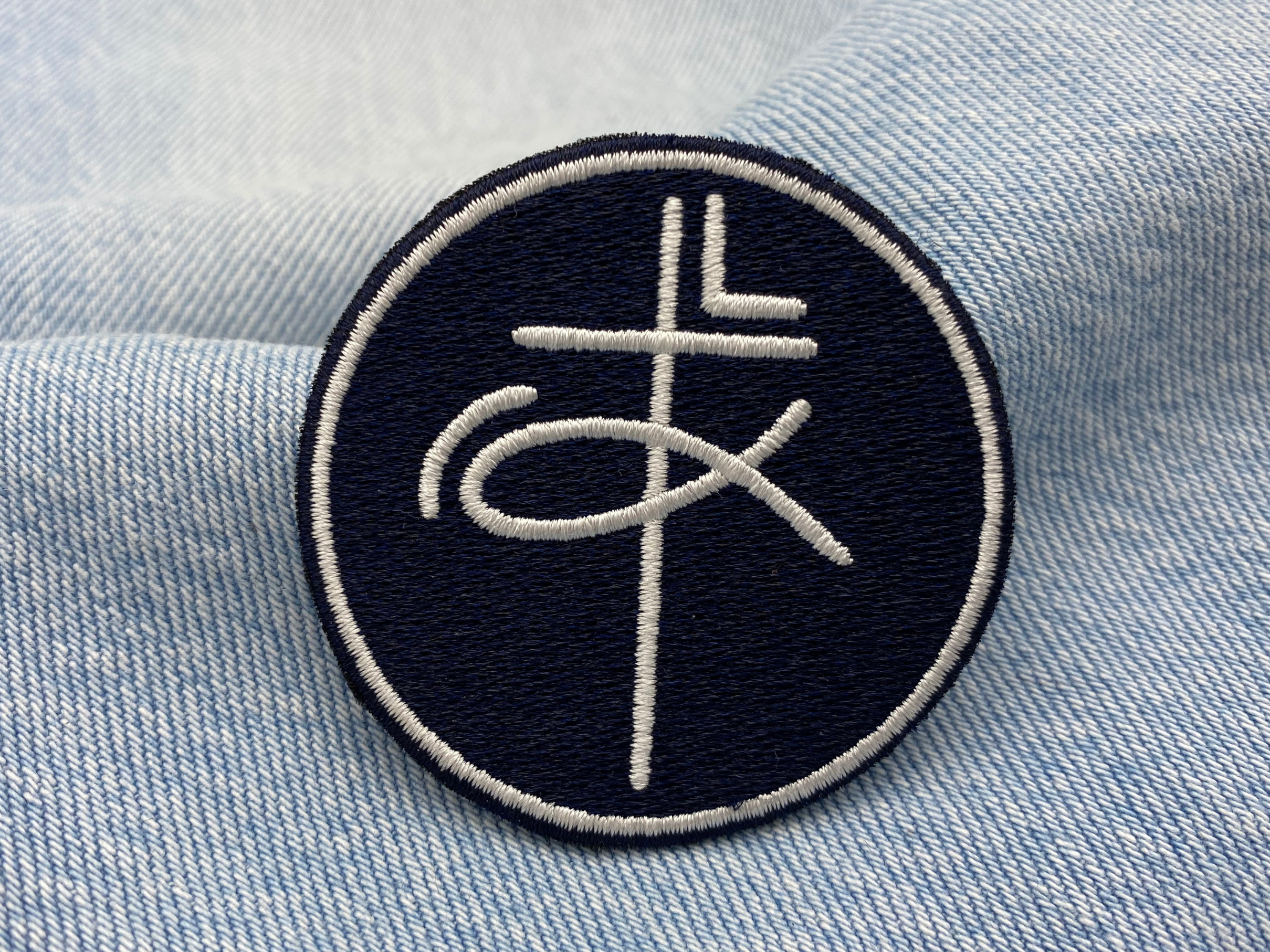 Kreuz & Fisch Patch auf blauer Jeans
