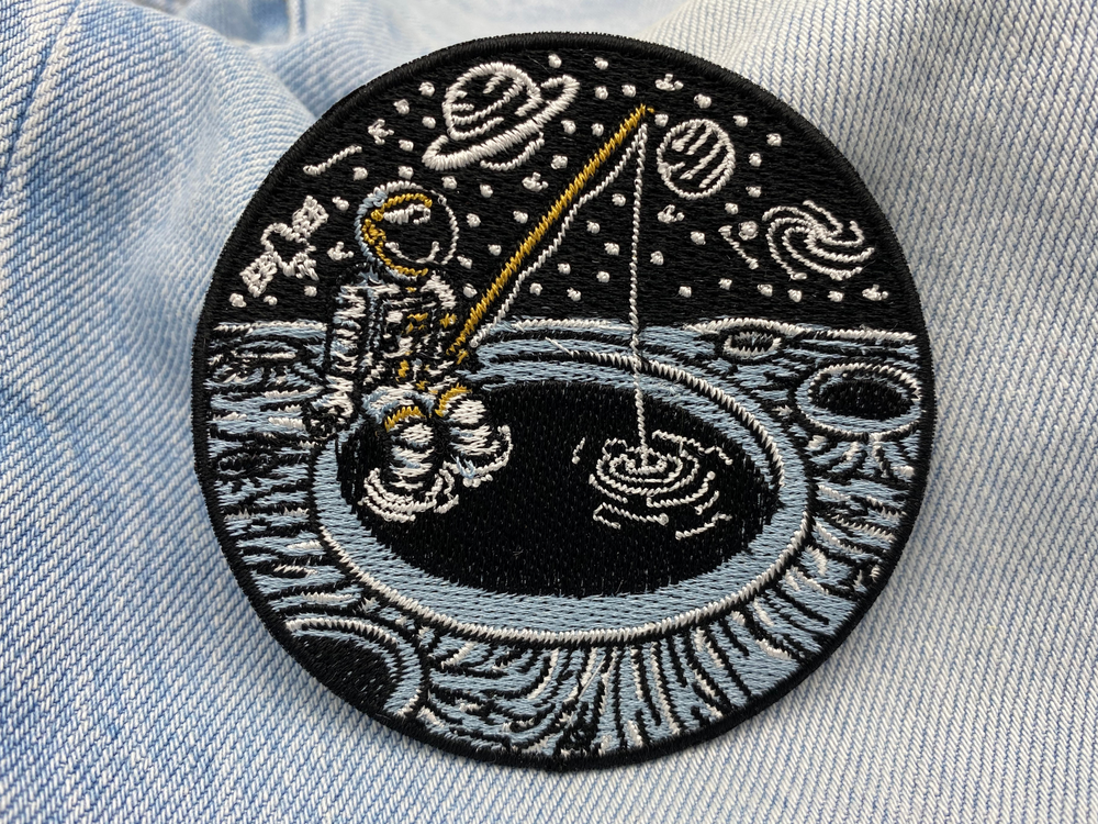 Angelnder Astronauten Patch auf blauer Jeans