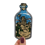 Frauenhand hält den Wüste in der Flasche Patch