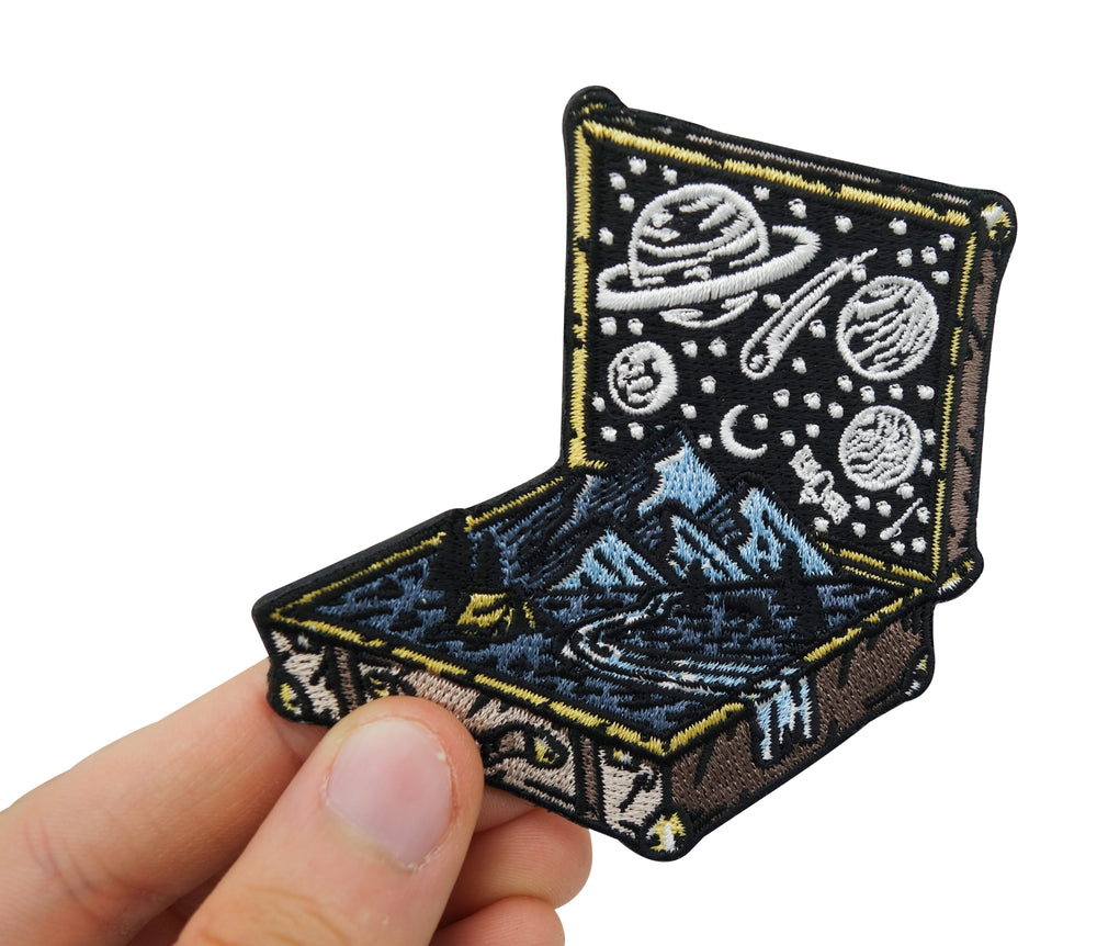 Welt im Koffer Patch gehalten von einer Hand